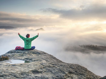 Man standing on rock against sky