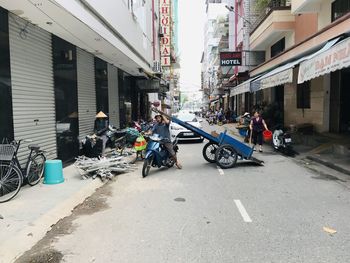 People riding motorcycle on street against buildings in city