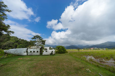 Abandoned vehicle on field against sky