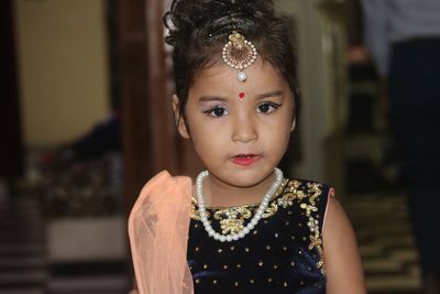 Portrait of cute girl wearing traditional clothing standing at home