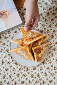 Close-up of person hand holding toasted bread on table