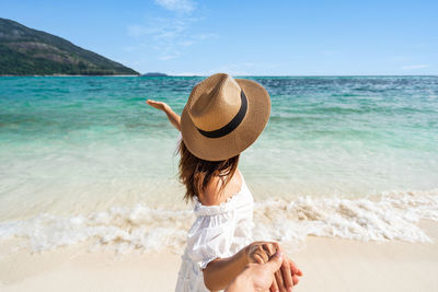 Woman wearing hat at beach against sky