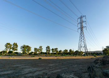 Electricity pylons on field against clear sky