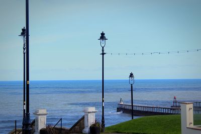 Street light by sea against clear sky