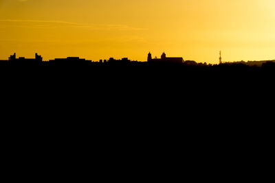 Silhouette buildings against sky during sunset