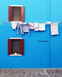 Clothes drying against blue wall of building