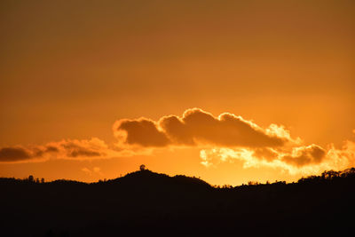 Silhouette landscape against dramatic sky during sunset