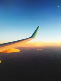 Airplane wing against clear sky during sunset