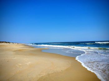 Scenic view of beach against clear blue sky