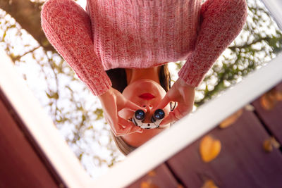 Reflection of woman looking through binoculars in mirror