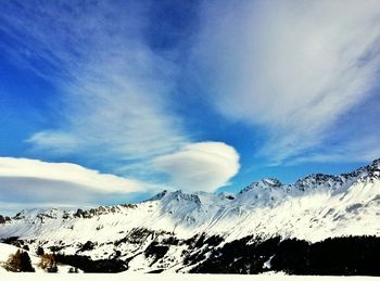 Scenic view of snow covered mountains against blue sky