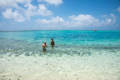 Rear view of shirtless friends snorkeling in sea