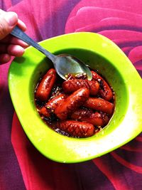 Close-up of hand holding strawberry in bowl