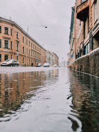 Canal amidst buildings in city during rainy season
