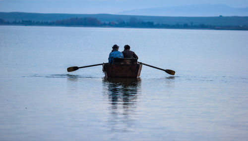 Rear view of people boating on lake