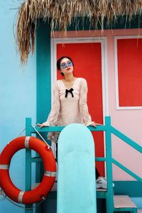 Young woman standing in front of a colorful beach hut