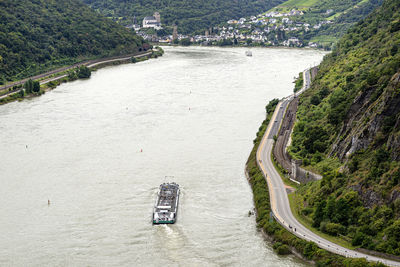 A tanker barge sailing on the river rhine in western germany, visible road and railroad tracks.