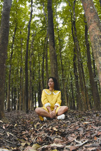 Young man sitting on tree trunk in forest