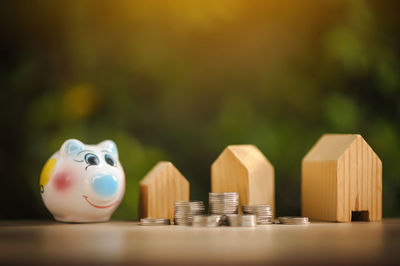 Close-up piggy bank with coins and model home on table