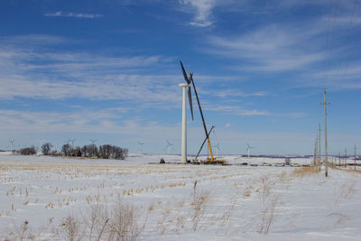 Windmills on field against sky during winter
