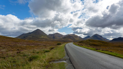 Road leading towards mountains against sky