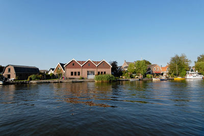 Houses by river and buildings against sky