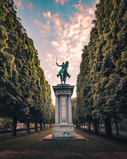 Statue in park against cloudy sky