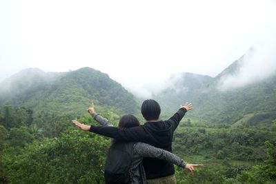 Rear view of couple standing on mountain against sky