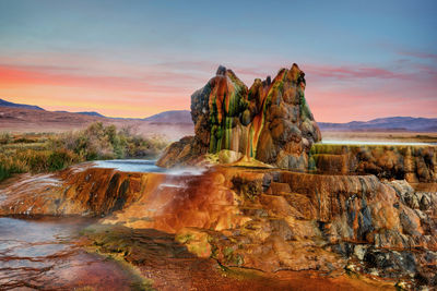 Rock formation on land against sky during sunset