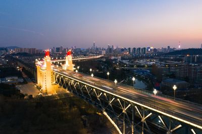 Illuminated bridge in city against sky at night