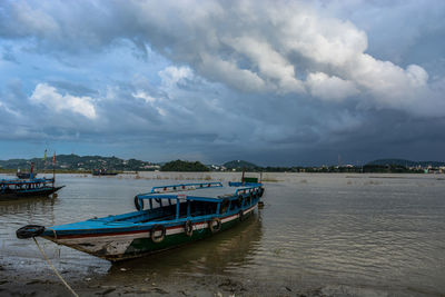 Boats moored on river against sky