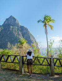 Rear view of woman walking on bridge against sky