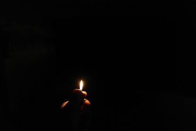 Close-up of lit candle in dark room