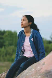 Young woman sitting against sky