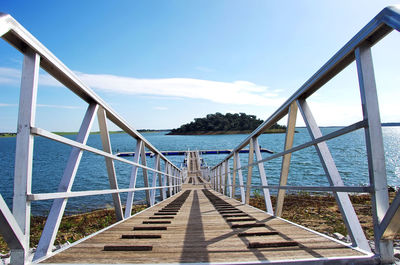 Pier leading towards alqueva dam against sky