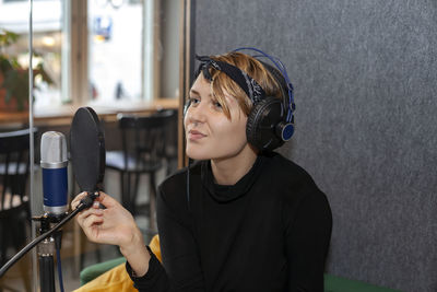 Woman wearing headphones and sitting at table with microphone