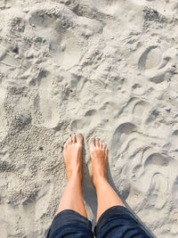 Low section of person standing on sand