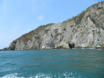 Scenic view of sea and rocks against blue sky