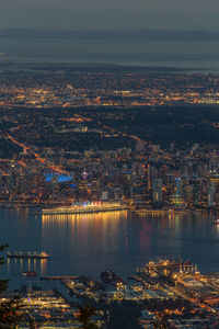 Aerial view of harbor amidst illuminated cityscape at night