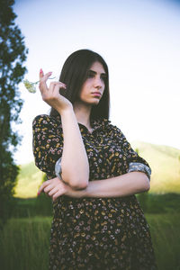 Thoughtful young woman looking away while standing against clear sky