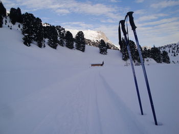 Ski poles on snow covered field against sky