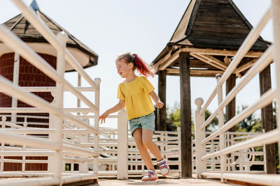 Full length portrait of young woman standing against built structure