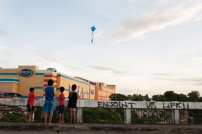 Rear view of children against sky in city