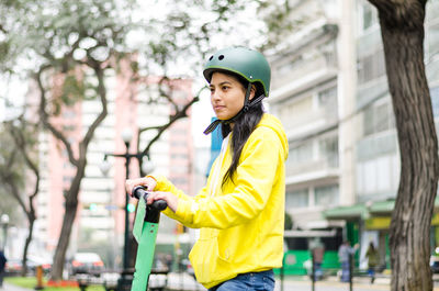 Young woman standing against yellow and trees