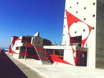 Red flag against built structure against clear blue sky