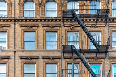 Yellow brick facade, and pair of boots hanging of the fire stairs. chelsea, nyc.