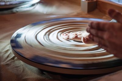 Close-up of hands on pottery wheel