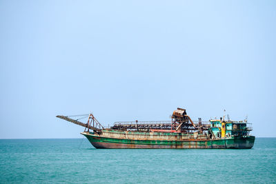 Fishing boat in sea against clear sky