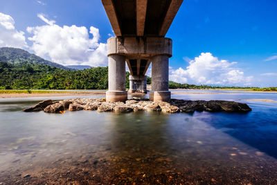 Below view of bridge over river against blue sky