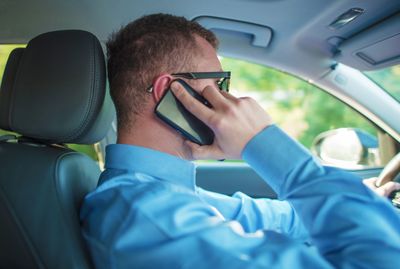 Side view of man talking on phone while sitting in car